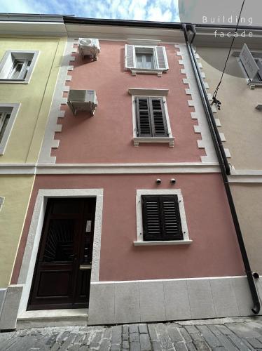 a pink building with two windows and a door at Piran Rooftop Apartments in Piran