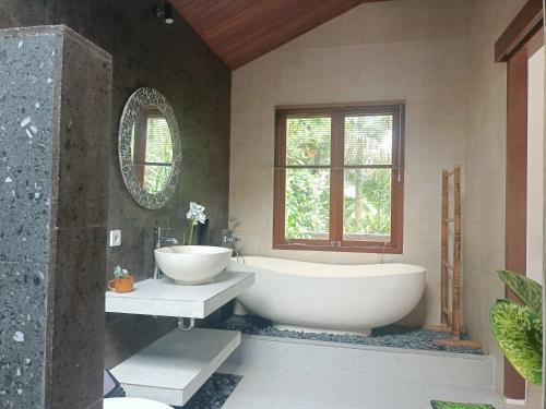 a bathroom with a tub and a sink and a window at Ubud Dream House Villa in Ubud