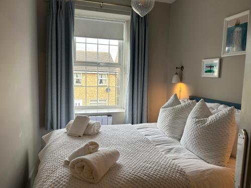 a bedroom with two towels on a bed with a window at Coral Cottage Amble in Amble