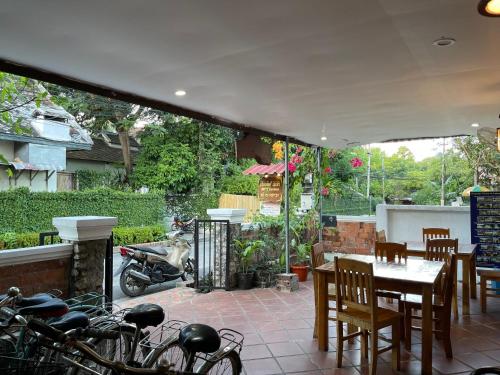 un patio con mesa, sillas y motocicletas en Liberty Place, en Luang Prabang