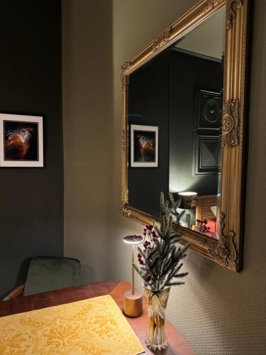 a room with a table with a mirror and a vase with flowers at La Chambre des Trois Églises in Riquewihr