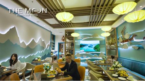 two people sitting at tables in a restaurant at The Moon Boutique Hotel Cat Ba in Cat Ba