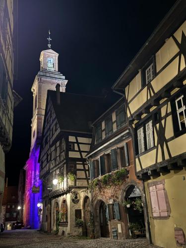 a building with a clock tower at night at La Chambre des Trois Églises in Riquewihr