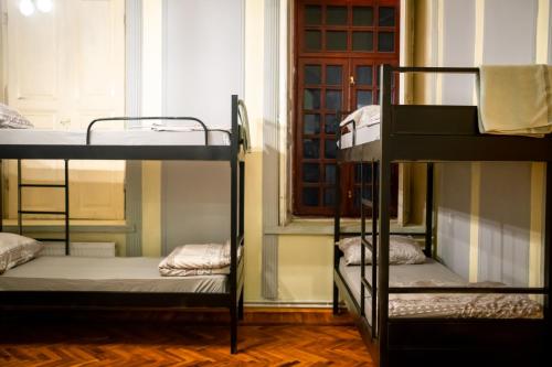 a room with three bunk beds and a window at Flora Music & Art Hostel in Baku