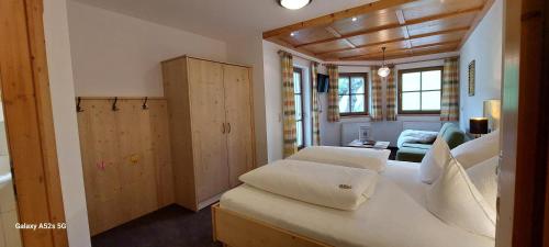 Zimmer mit einem großen weißen Bett und einem Wohnzimmer in der Unterkunft Hof Unterhuben in Fügenberg