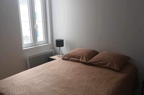 een bed met twee kussens en een lamp op een tafel bij Appartement de l'EST N°2 in Montluçon