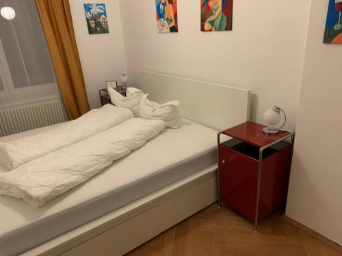 a bed with white sheets and a red night stand at Apartment Grossman in Hradec Králové