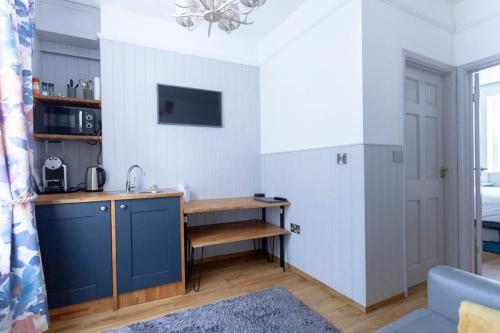 a small kitchen with a blue cabinet and a table at Ground floor apartment at Number 8: king bed, en-suite, lounge, kitchenette in Kent