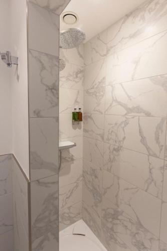 a bathroom with a shower with marble walls at Ground floor apartment at Number 8: king bed, en-suite, lounge, kitchenette in Kent