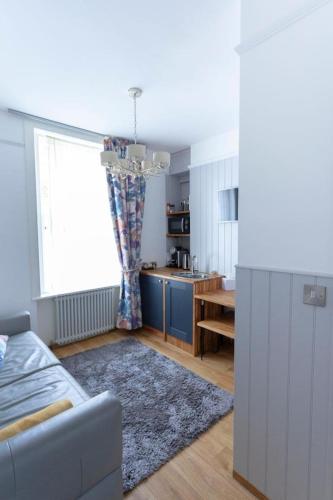 a living room with a couch and a kitchen at Ground floor apartment at Number 8: king bed, en-suite, lounge, kitchenette in Kent