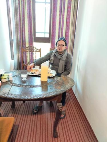 a woman sitting at a table with a plate of food at Sea Green Guest House in Srinagar