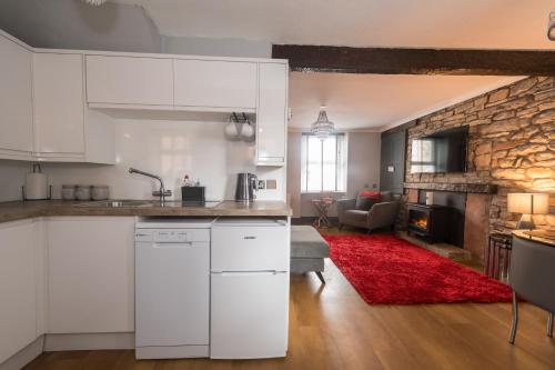 a kitchen with white cabinets and a living room at Crown and Cushion Appleby in Appleby