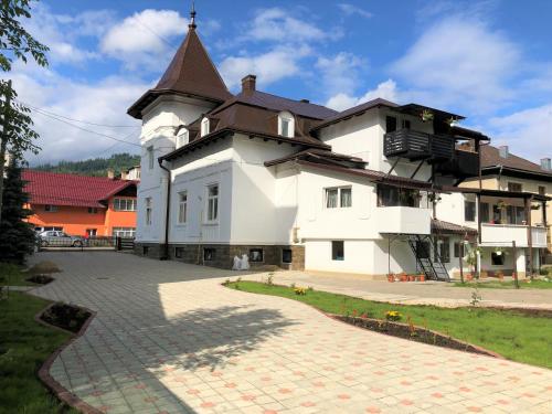 Un gran edificio blanco con una torre en la parte superior. en Villa Coca, en Câmpulung Moldovenesc