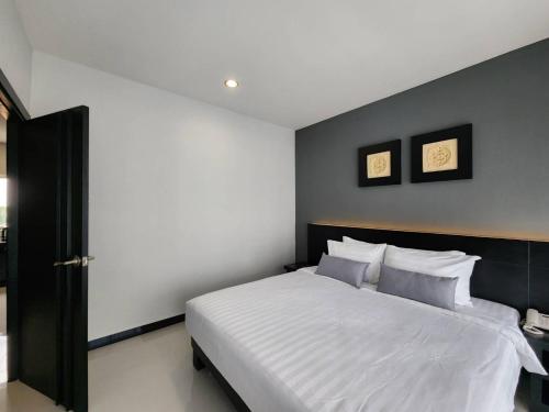um quarto com uma cama branca e duas fotografias na parede em LHC HOTEL AND RESORT em Pattaya Central