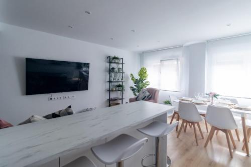uma sala de estar com uma grande mesa branca e cadeiras em Lujoso apartamento entre 2 playas con garaje em Gijón