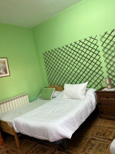 a bedroom with two beds and a green wall at Hostal Cabañeros in Ciudad Real