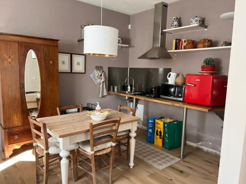 cocina con mesa de madera con sillas y nevera roja en B&B La Mammola, en Lugo