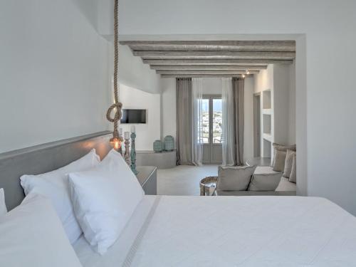 a bedroom with a white bed and a living room at Hotel Papadakis in Naousa