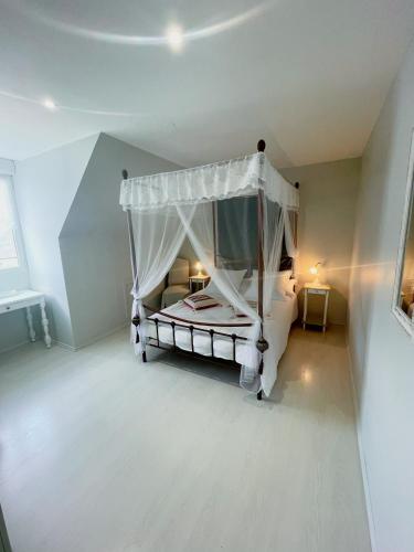 une chambre avec un lit blanc à baldaquin dans l'établissement maison philirina, à Athée-sur-Cher