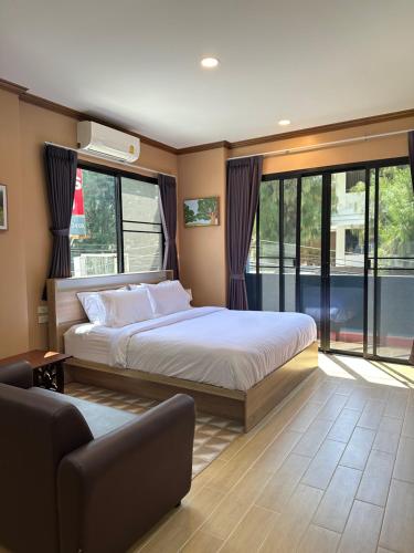 a bedroom with a bed and a couch and windows at Kata Noi Place in Kata Beach