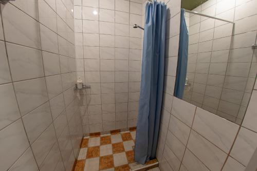 a shower with a blue shower curtain in a bathroom at Hostel Viktorija with Private Rooms in Rīga