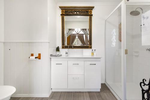 Baño blanco con lavabo y espejo en Harem Cottage Gembrook - Spa Bath & Wood Fireplace en Gembrook