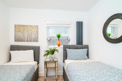 2 camas en una habitación con paredes blancas y espejo en Modern 2 bed apartment close to Westfield Stratford mall with garden en Londres