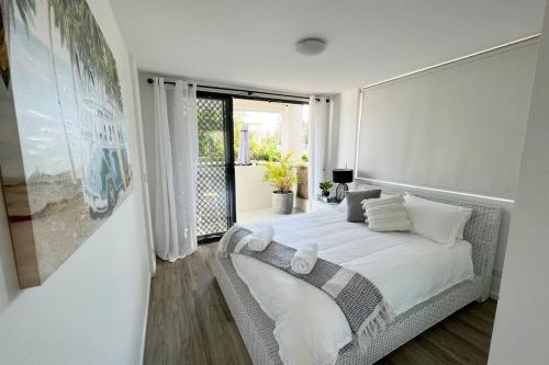 een slaapkamer met een bed en een groot raam bij Beach Pad Private Town house Sea Views Dual living 5 Beds in Redcliffe