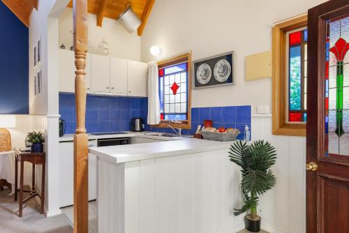 a kitchen with a white counter and blue tiles at Bluebell Cottage Gembrook - Heated Spa & Wood Fireplace in Gembrook