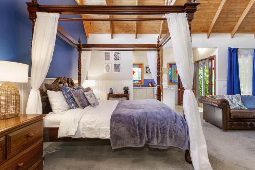 una camera con letto a baldacchino e divano di Bluebell Cottage Gembrook - Heated Spa & Wood Fireplace a Gembrook