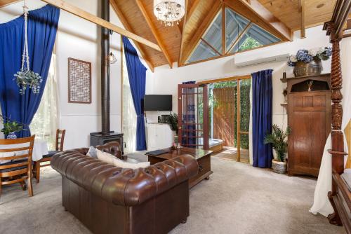 a living room with a leather couch and blue curtains at Bluebell Cottage Gembrook - Heated Spa & Wood Fireplace in Gembrook