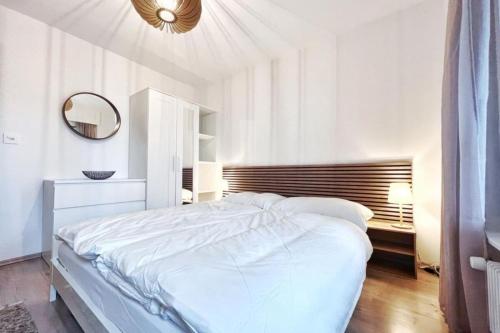 um quarto branco com uma cama grande e um espelho em Brin de Mousse I 49 m I Balcony I Peace and greenery em Crans-Montana
