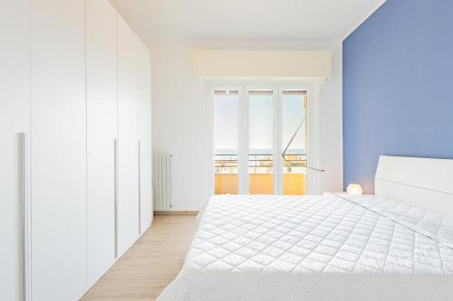 a white bedroom with a white bed and a window at Appartamento vista mare di Marco in Spotorno