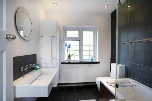 a bathroom with a tub and a sink and a mirror at Hömli-Cosy-Spacious-GardenView in Sileby