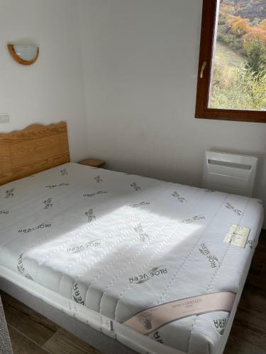 Ce lit se trouve dans un dortoir doté d'un couvre-lit blanc. dans l'établissement Le Valmignon, à Valmeinier