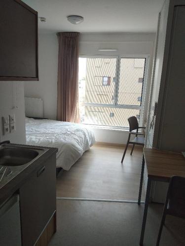 ein Schlafzimmer mit einem Bett und einem großen Fenster in der Unterkunft Citadines Appart Suites Paris Center Easy - Eiffel Tower View - 25 minutes Champs Elysees in Châtillon