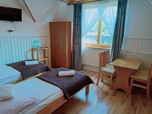 a bedroom with two beds and a desk and a window at Noclegi U Reni in Białka Tatrzańska