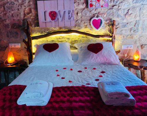 Un dormitorio con una cama con corazones en las almohadas en Casa Rustic Suites, JACUZI & LOVE, en Chert