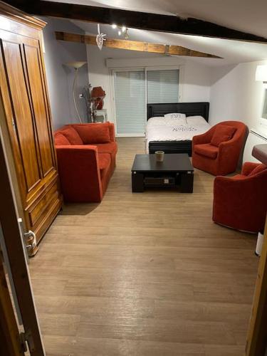 - un salon avec deux chaises orange et un lit dans l'établissement Rez de maison jardin appart, à Saint-Pont