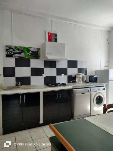 a kitchen with a black and white checkered wall at Appart la Percep in La Tour-dʼAuvergne
