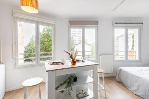 a white bedroom with a bed and a table and two chairs at Le Havre du Bonheur in Saint-Denis