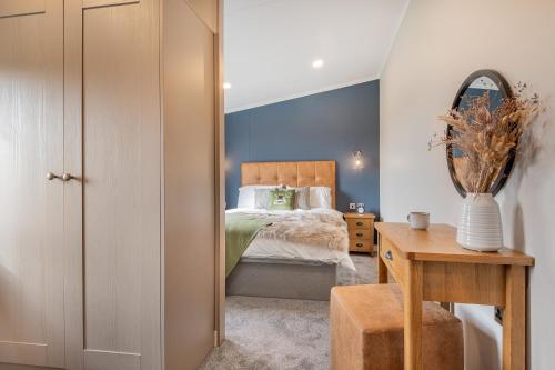 a bedroom with a bed and a table with a mirror at Oak Tree Timber Holiday Lodge in Bassenthwaite