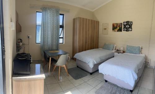 een slaapkamer met 2 bedden, een tafel en een bureau bij Phindulo Bed and Breakfast - No Loadshedding, Smart TVs & unlimited free fibre wifi in Krugersdorp