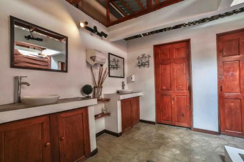 La salle de bains est pourvue d'un lavabo, d'un miroir et d'une porte. dans l'établissement Pipe House Luxury Beach Glamping Retreat, à Barco Quebrado