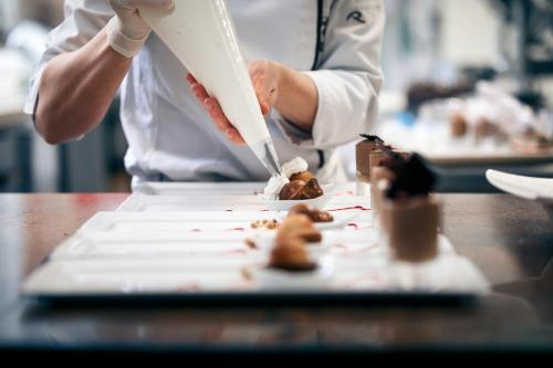 a chef preparing food on a plate on a table at Le Rosenmeer - Hotel Restaurant, au coeur de la route des vins d'Alsace in Rosheim