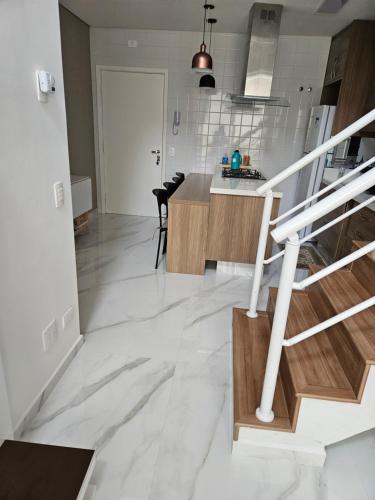 cocina y sala de estar con paredes blancas y suelo de mármol en Gaudi Loft Design, en Campos do Jordão