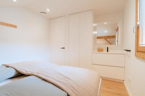 een witte slaapkamer met een bed en een kast bij Bright & elegant stand alone chalet - 8 ppl - Vois Le Mont in Les Gets