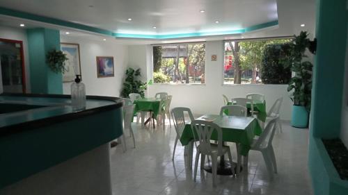 een eetkamer met groene tafels en stoelen bij HOTEL PARQUE VIA in Mexico-Stad