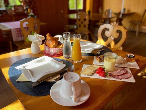 Le Rosenmeer - Hotel Restaurant, au coeur de la route des vins d'Alsace في Rosheim: طاولة خشبية عليها طعام ومشروبات للإفطار