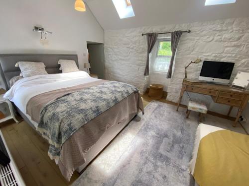 a bedroom with a bed and a desk with a television at Oranuisce Thatch Cottage Ballyvaughan in Ballyvaughan